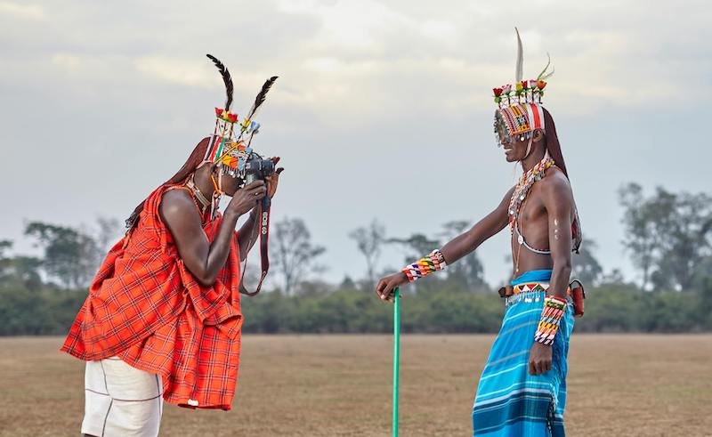 Men wearing Ugandan traditional attire taking photos.